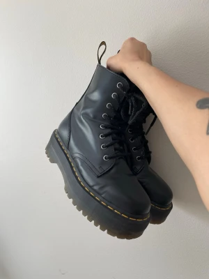 Svarta Dr. Martens Jadon kängor - Säljer ett par svarta Dr. Martens Jadon kängor i läder med grov platåsula och klassiska gula sömmar. Kängorna har snörning framtill och dragflik bak med logga. Använda några gånger men väl omhändertagna 