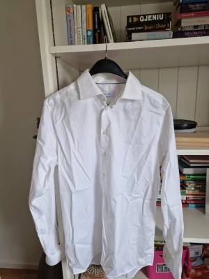 Vit skjorta från Eton - Klassisk vit skjorta från Eton med krage och knäppning framtill. Skjortan är långärmad och har en stilren, tidlös design som passar till många olika looks. Tillverkad i bomull för en skön känsla och snygg passform.