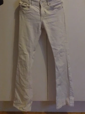 Vita bootcut jeans - Säljer ett par vita bootcut jeans med klassisk femficksdesign och knappstängning. Jeansen har raka ben och är tillverkade i ett mjukt denim-material som är bekvämt att bära. Perfekt för dig som vill ha en clean och stilren look.