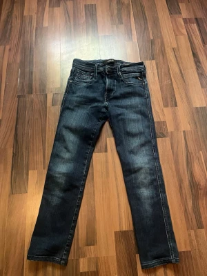 Blå Replay jeans med smal passform - Snygga blå jeans från Replay med smal passform och klassisk femficksdesign. Jeansen har en mörk tvätt med lätt slitning, Replay-logga på fickan och bak på linningen. Tillverkade i stretchigt denim för extra komfort. W27 l30