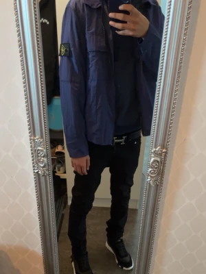 Blå lättviktsjacka från Stone Island - Säljer en blå lättviktsjacka från Stone Island med klassisk patch på vänster ärm. Jackan har en avslappnad passform, dragkedja framtill och är tillverkad i ett tunt, krispigt material som passar perfekt till lager-på-lager-stil. Stone Island plast påse ingår skriv om du har några funderingar!!!