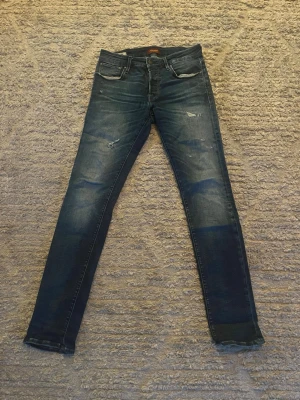Jack&jones - Säljer dessa fina jack&jones jeans i en blå färg med fina design slitningar. Fint skick på jeansen 9/10. Storlek W32L33  
