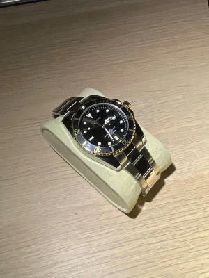 BiDen Quartz svart/guld klocka - Snygg klocka med svart urtavla och gulddetaljer. Klockan har en klassisk rund form, svart vridbar bezel och länkarmband i silver. Perfekt accessoar för dig som gillar exklusiv stil och tidlös design.
