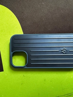 Blått mobilskal från Rimowa - Snyggt blått mobilskal från Rimowa med räfflad design och diskret logga på baksidan. Tillverkat i tålig plast och har en öppning för kameran. Passar perfekt för dig som vill ha ett stilrent och robust skydd till din mobil.