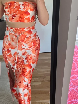 Figursydd klänning med orangea blommor - Köpt i Kroatien, stretchigt material. Storlek S, har inbyggd bh! 