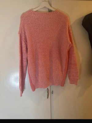  Rosa stickad oversized tröja - Mysig stickad tröja i en härlig rosa nyans. Oversized passform med rund halsringning och långa ärmar. Ribbstickade muddar vid ärmslut och nederkant. Perfekt för lager på lager och chill dagar.