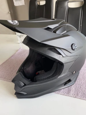 Svart moped/crosshjälm  - Säljer denna moppehjälm/cross då den ej används, väldigt bra skick, nypris 500 tror jag. Storlek S och använd fåtal gånger. 