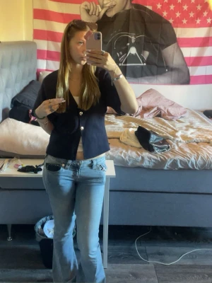 Mörkblå kortärmad kofta med knappar - Snygg mörkblå kofta med korta ärmar och två stora guldiga knappar, perfekt att slänga över ett linne eller t-shirt. Materialet känns mjukt och stretchigt. Knappt använt och ser helt ny ut, säljer då den är lite för stor💗💗