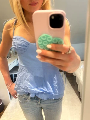 Ljusblå linnetopp med knytband - supersöt ljusblå linnetopp med smala axelband och knyt vid axlarna. toppen har en lätt rynkad byst och volangkant nertill för en feminin look. perfekt till jeans eller kjol för en fräsch sommarstil. toppen har fått några små ”stänk” av klor på baksidan där av priset 🥹 från zara i stl s endast använd ett fåtal gånger !! säljer snabbt - först till kvarn 🩵🩵 hör av dig vid frågor !