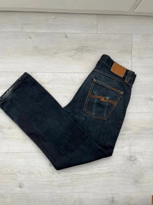 Mörkblåa nudie raw jeans - Säljer ett par mörkblåa raw denim jeans från Nudie Jeans i regular fit. Riktigt clean och stilrena jeans som formar sig snyggt efter användning.  • Färg: Mörkblå raw denim • Fit: Regular fit • Skick: Bra skick • Tjock och kvalitativ denim • Perfekta för en clean och tidlös stil • Snygga både uppvikta och som de är