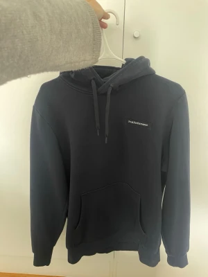 Mörkblå hoodie - Mörkblå hoodie från Peak Performance i strl M. Använd fåtalet gånger. Nypris runt 1000kr