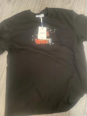 Svart Off-White t-shirt med tryck - Svart t-shirt från Off-White med färgglatt tryck framtill och stort motiv på ryggen med Tom från Tom & Jerry i basketkläder. Rund halsringning och korta ärmar. Perfekt för dig som gillar streetwear och coola prints.