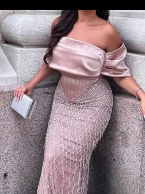 Lång rosa offshoulderklänning - Elegant långklänning i rosa färg med offshoulder-design och glittriga detaljer. Överdelen är i glansigt satinliknande material och kjolen har ett nätmönster med pärlliknande dekorationer. Perfekt för bal eller fest. Klänningen är i storlek 42 men Insydd till storlek 36/38, köptes för 6000kr och användes endast i några timmar , pris kan diskuteras vid snabb affär 🥰