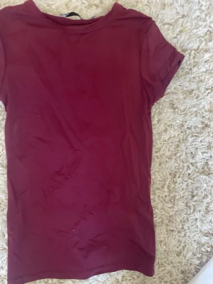 Vinröd t-shirt från 157 - Enkel och stilren vinröd t-shirt från 157 i mjuk bomull. Klassisk rund halsringning och korta ärmar. Perfekt basplagg att matcha med allt i garderoben.