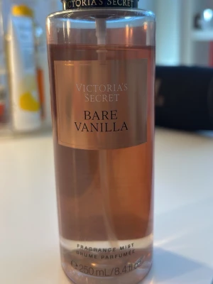Victoria's Secret Bare Vanilla mist - En lyxig doftmist från Victoria's Secret i doften Bare Vanilla. Flaskan är genomskinlig med roséguld etikett och innehåller 250 ml. Doften har inslag av vispad vanilj och mjuk cashmere för en varm och mysig känsla. Nästan full men använd.