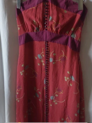 Marc Jacobs runway haute couturesilk dress  -  Marc Jacobs runway haute couture silk dress  den exklusiva huvudlinjen Marc Jacobs Runway (Black Label) Storlek 12, motsvarande M/L (beroende på byststorlek ) Bröst 48cm Längd 104-108 cm Underbar klänning i silke med halterneck-design och en livfullt mönstrad röd överdel. Klänningen har dekorativa knappar längs framsidan och en kontrasterande enfärgad kant upptill och i midjan. Den är fodrad med ett ljust tyg som skapar en fin volym nertill.