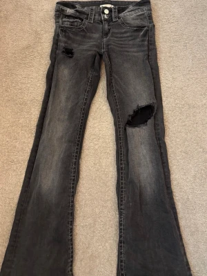 Gråa håliga bootcut jeans strl 152 tall - Jag säljer ett bar gråa bootcut jeans med låg midja. Jag har gjort 2 egna hål,ett på knät och uppe vid låret. De är också uppsydda av en skräddare så de är ungefär lika långa som ett par vanliga jeans som är i strl 152 från Gina Tricot.