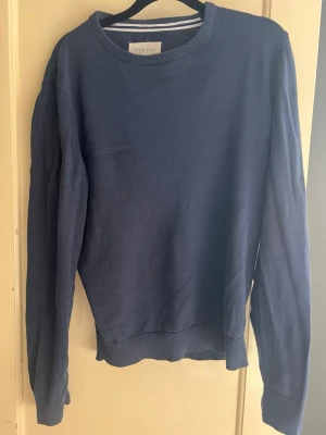Mörkblå tröja från Pier One - Snygg mörkblå tröja från Pier One med rund halsringning och ribbade muddar vid ärmslut och nederkant. Enkel och stilren design som passar perfekt till jeans eller chinos. Materialet känns mjukt och bekvämt mot huden. Passar om du är runt 175cm.