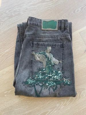 Derschutze Jesus Embroidery Wide Leg Jeans – Washed Grey – Brand New with tags - Derschutze jeans in washed grey denim with large detailed Jesus embroidery on the back pocket extending down the leg. Wide leg fit. Brand new with tags, never worn. Rare piece from one of streetwear’s most hyped emerging brands. Selling for 800 SEK. Shipping not included, local pickup possible.
