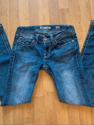 Blåa bootcut jeans från Bik Bok - Snygga blå bootcut jeans från Bik Bok med slitningar och kontrastsömmar. Klassisk femficksmodell och låg midja. Perfekta för en avslappnad och trendig look.