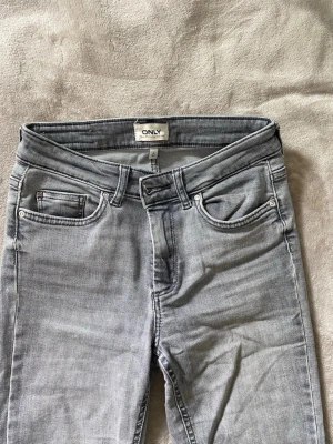 Ljusgrå bootcut jeans från only - Köpt på SALT. Ljusgrå och bootcut. Midwaist/lowwaist. Lite trasig nere på ena byxbenet.