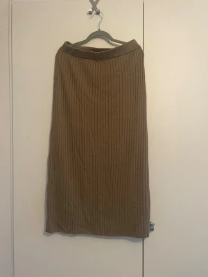 Stickad kjol  - Säljer en brun långkjol med ribbad struktur. Kjolen har en enkel och stilren design med raka linjer och mjukt material som ger en skön passform. Perfekt att matcha med en stickad tröja eller crop top för en trendig look.