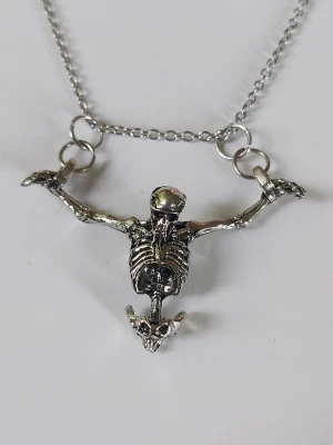 Halsband dödskalle  - Silvrigt halsband hängande dödskalle med halva skelettet och fina konturer i detaljer. Materialet rostfritt stål. 