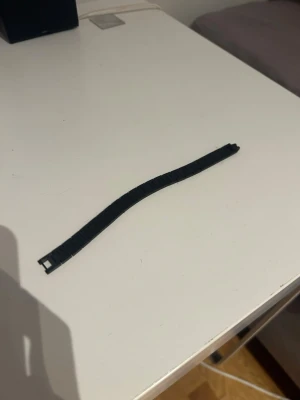 Svart Lacoste länkarmband  - Säljer ett svart Lacoste länkarmband i plast. Armbandet har en klassisk design med rektangulära länkar och enkel låsning. 