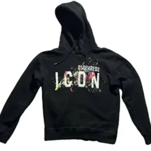 Svart hoodie Dsquared2 ICON - Svart hoodie från Dsquared2 med stor vit 'ICON'-text och färgstänk på bröstet. Klassisk huva med dragsko och ribbade muddar vid ärmar och midja. Perfekt för dig som gillar streetwear och vill sticka ut med en snygg logga.