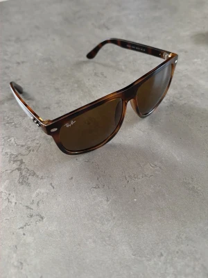 Bruna Ray-Ban boyfriend solglasögon - Snygga solglasögon från Ray-Ban i klassisk boyfriend-modell. Bågarna är bruna med sköldpaddsmönster och glasen är mörka. Perfekta för soliga dagar och ger en cool vibe till din outfit.