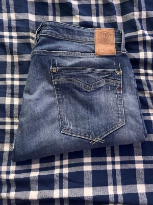 Replay jeans  - Säljer ett par klassiska blå jeans från Replay  med raka ben och snygga slitningar. modell Newbill. JAG SKICKAR EJ FLER BILDER PÅ JEANSEN! för storleksguide hänvisar jag till måtten och för bättre inblick i passformen rekommenderar jag att googla på modellnamnet.JAG TAR EJ EMOT RETURER. kom ej med bud om du ej köper efter:)