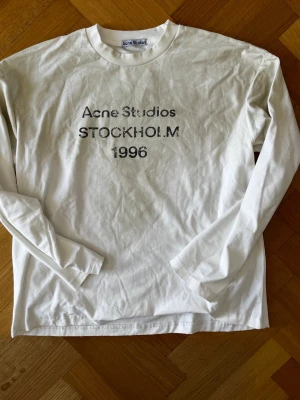 Vit långärmad Acne Studios t-shirt - Säljer en vit långärmad t-shirt från Acne Studios med tryck på bröstet där det står 'Acne Studios STOCKHOLM 1996'. Klassisk rund hals och relaxed fit. Tillverkad i bomull och true hemp som känns skön mot huden. Köpt i butik