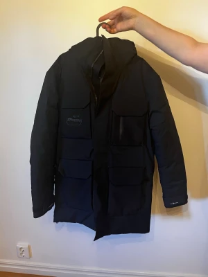 Sail Racing jacka  - Snygg svart parkas från Didriksons med fyra stora fickor framtill och varm, quiltad insida. Jackan har huva och dragkedja med vindslå. Perfekt för kalla dagar och har en stilren, modern look. Helt ny sail racing jacka köptes för 7000. Pris  kan diskuteras😊