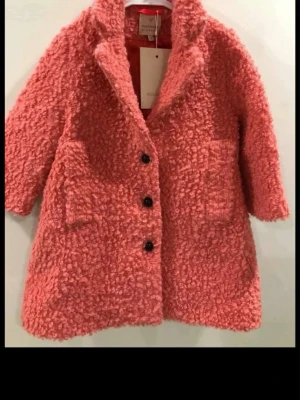 Rosa teddyjacka från Roksanda Blossom - Säljer en fluffig rosa teddyjacka från Roksanda Blossom. Jackan har tre svarta knappar framtill, två stora fickor och en oversized krage. Materialet är mjukt och lurvigt, perfekt för dig som vill ha en statementjacka med cozy vibe.