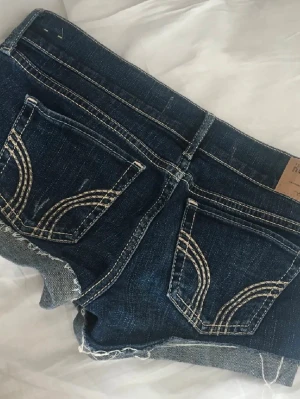 Mörkblå jeansshorts från Hollister - Snygga mörkblå jeansshorts från Hollister låg midjade. Storlek w26 motsvarar ungefär s