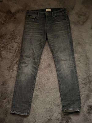 Grå slim fit jeans jack & jones - Snygga grå slim fit jeans med klassisk femficksdesign och diskreta slitningar framtill. Jeansen har normal midja och raka ben, perfekta till en avslappnad streetstyle-look. Tillverkade i mjukt denimtyg för skön känsla.