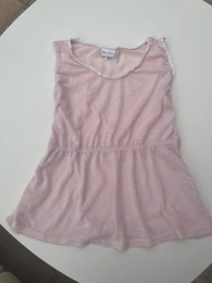 Ljusrosa babydoll-topp från Miss Linda - Söt ljusrosa topp från Miss Linda med ärmlös design och rund halsringning. Toppen har en lätt rynkad midja och dekorativ spetsdetalj längs halsen och ärmhålen. Perfekt för varma dagar och enkel att matcha med jeans eller shorts. Har ni några frågor eller vill ha bilder/mått så bara säg till!! 💞