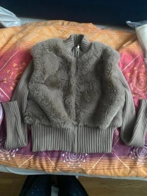 Beige pälsjacka från Bershka - Snygg beige cardiganjacka från Bershka i storlek XS. Jackan har ribbstickade ärmar och midja samt mjuk fuskpäls framtill. Dragkedja framtill och hög krage ger en cool och mysig look. Perfekt för lager på lager och trendiga outfits 🩵