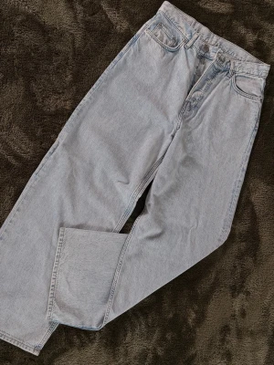 Ljusblå baggy jeans från Weekday - Säljer ett par ljusgrå jeans från Weekday, modell ASTRO. Jeansen har baggy passform och klassisk femficksdesign. Tillverkade i 100% bomull för en skön och avslappnad känsla. Perfekta för dig som gillar en clean och enkel stil. aldrig använt 
