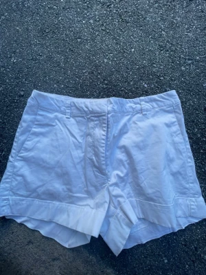 Vita shorts från H&M Conscious - Snygga vita shorts från H&M Conscious Collection med klassisk passform och bälteshällor. Gjorda i mjuk bomull, perfekta för varma dagar. Stängs med dragkedja och knapp framtill. Stilrena och lätta att matcha till olika outfits.