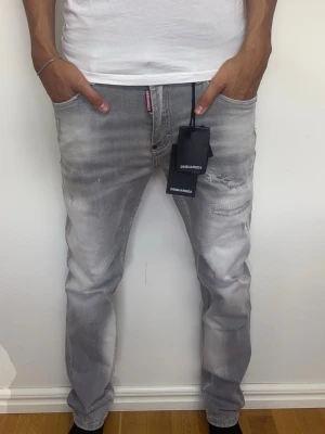 Ljusgråa Dsquared2 slimfit jeans med slitningar  - Ett par väldigt fina gråa slimfit jeans från dsquared med slitningar | Storlek 33, 41 cm i midjan och 101 cm i längd | Fraktar samma dag om köp sker innan 22:00