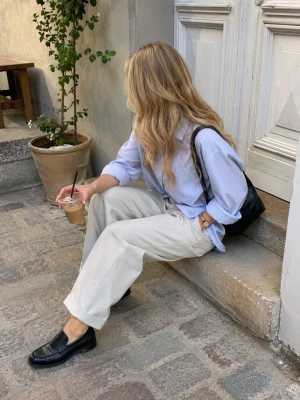 Svarta loafers i skinn - Säljer ett par klassiska svarta loafers i skinn med rundad tå och bred rem över foten. Skorna har en stilren design och en diskret sula som passar till många olika outfits. Perfekta för dig som gillar en tidlös och clean look.