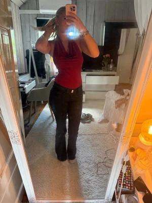 Svarta bootcut läderbyxor - Säljer ett par svarta bootcut läderbyxor med klassisk femficksmodell och knappgylf. Jeansen har en enkel och stilren look utan slitningar eller dekorationer. Passformen är figurnära upptill och utsvängda nedtill för en snygg siluett.