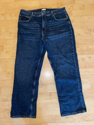 Mörkblå raka jeans - Säljer ett par mörkblå jeans med rak passform och klassisk femficksdesign. Jeansen har normal midja och är tillverkade i kraftigt denimtyg. Perfekta för en avslappnad och stilren look.