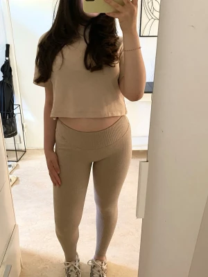 Beige ribbade leggings - Säljer ett par snygga beige ribbade leggings med hög midja och stretchigt material. De sitter väldigt bra på kroppen och är dessutom väldigt bekväma runt benen samt ger en trendig look.