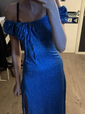 Blå sommarklänning - Supersöt blå klänning med vita prickar. Klänningen har snörning framtill vid bysten och en slits på sidan som ger en snygg detalj. Perfekt för sommarens alla tillfällen! 💙(Aldrig använd) 