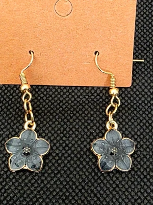 Handgjorda Blommiga örhängen i svart och guld - Snygga handgjorda örhängen med blommor i svart och guldfärgad metall. Blommorna har fem kronblad och små svarta detaljer i mitten. Hängande modell med krok, perfekta för att ge din look en unik touch.