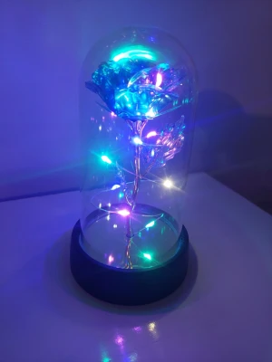 Glaskupa med LED-ros och ljusslinga - Säljer en dekorativ glaskupa med en konstgjord ros i metallfärg och inbyggd LED-ljusslinga som lyser i flera färger. Basen är svart och kupan är genomskinlig. Perfekt som cool inredningsdetalj eller present.