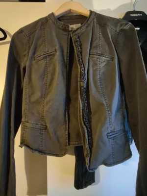 Grå figursydd jacka med detaljer - Snygg grå jacka tillverkad i ett mjukt bomullsliknande material. Perfekt till sommar.