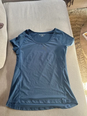 Blå tränings-tshirt från Energetics - Snygg blå tränings-tshirt från Energetics med rund halsringning och korta ärmar. Tillverkad i funktionsmaterial med Dry-Plus teknologi som transporterar bort fukt, perfekt för intensiva träningspass eller löpning.